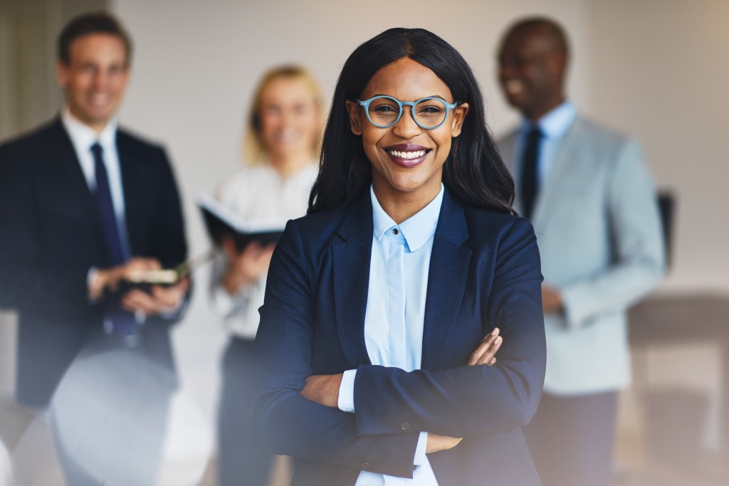 Confident Black woman leader smiling in a business setting, symbolizing career strategy and digital engagement support